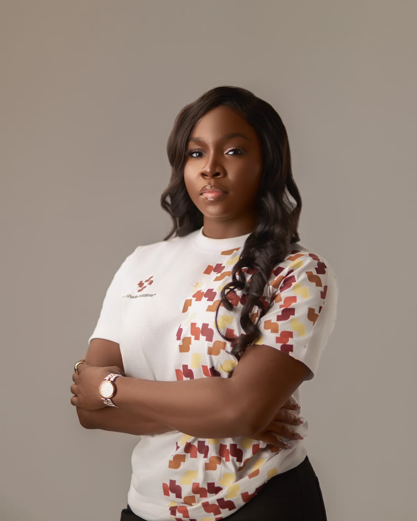 Portrait of Olabanke Oyinkansola Goriola, Founder and Lead Curator of The Black Frame, arms folded, wearing a Shade Initiative t-shirt.